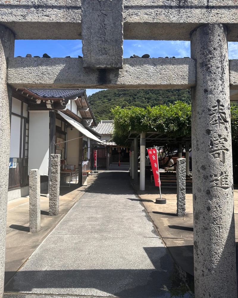 An old stone torii gate and a path leading to Hoto Shrine under a blue summer sky