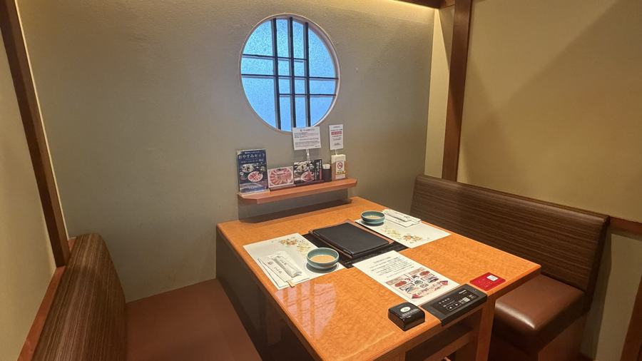 A private booth with a round window and a wooden table