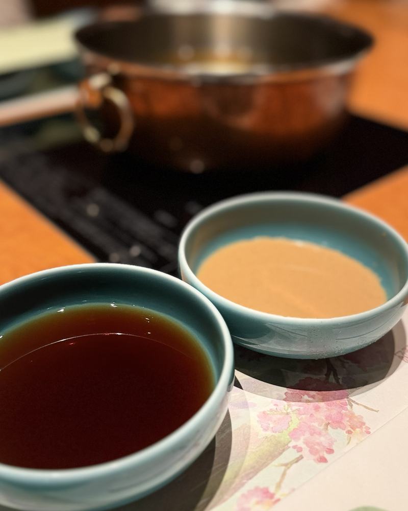 Two dipping sauces in blue bowls: a light sesame sauce and a darker sauce